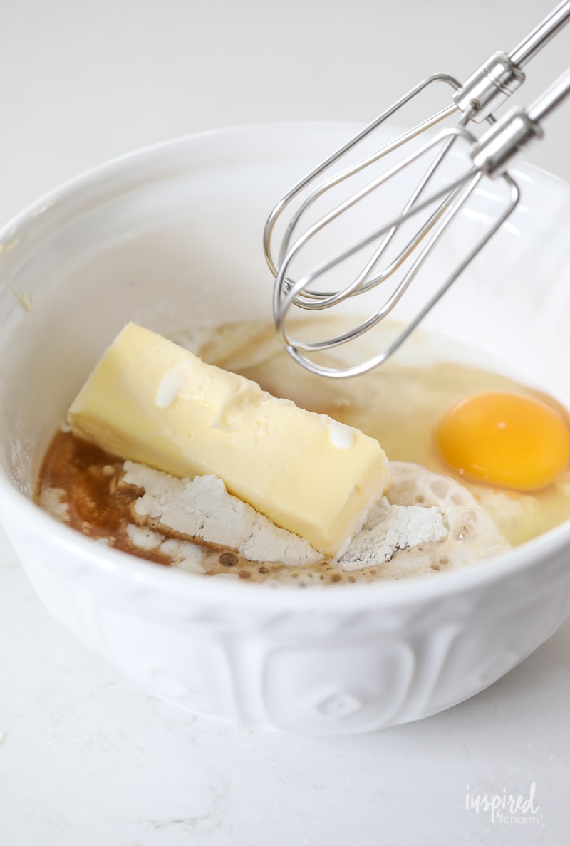 mixing bowl with cake batter, egg, stick of butter, and mixer. 
