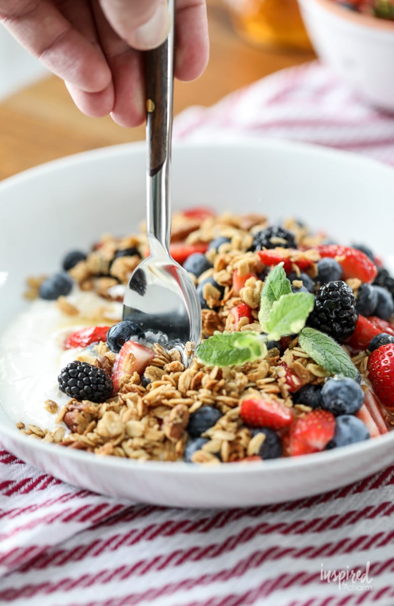 spoon with Yogurt with Granola Berries and Honey in a bowl.