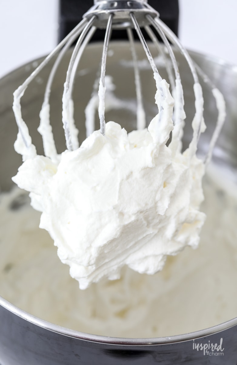 freshly made whipped cream on a whisk in a stand mixer