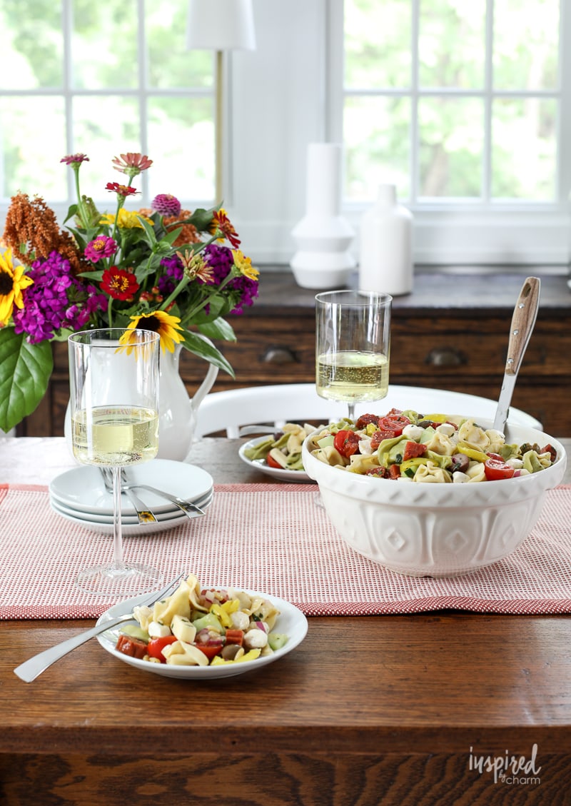 tortellini pasta salad in a large bowl and on plates on a table. 