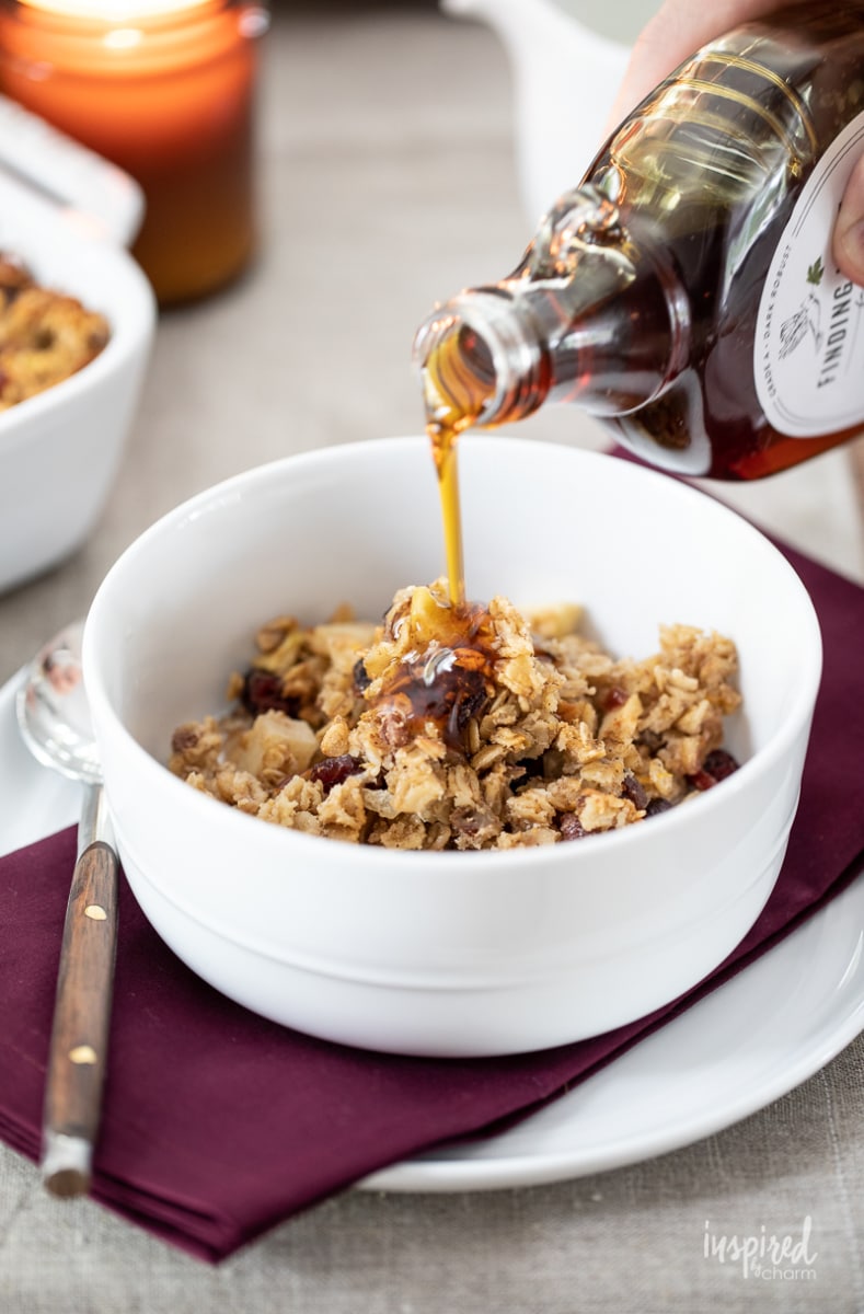 pouring maple syrup in a bowl of easy cranberry baked oatmeal 
