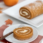 pumpkin roll on platter with a slice served on a plate.