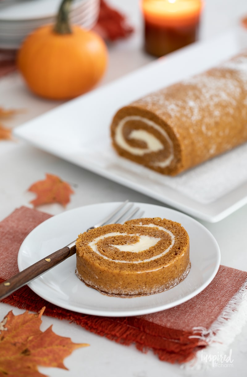 pumpkin roll on platter with a slice served on a plate.