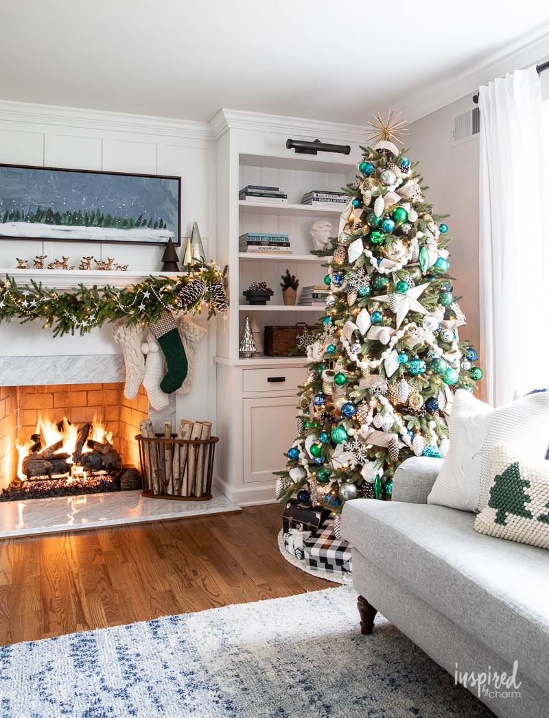 white living room with beautiful Christmas tree and matching garland along the mantel