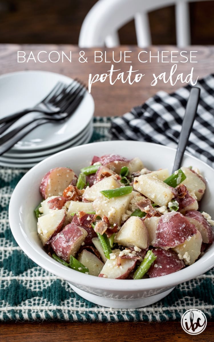 Bacon and Blue Cheese Potato Salad in a bowl with a stack of plates.
