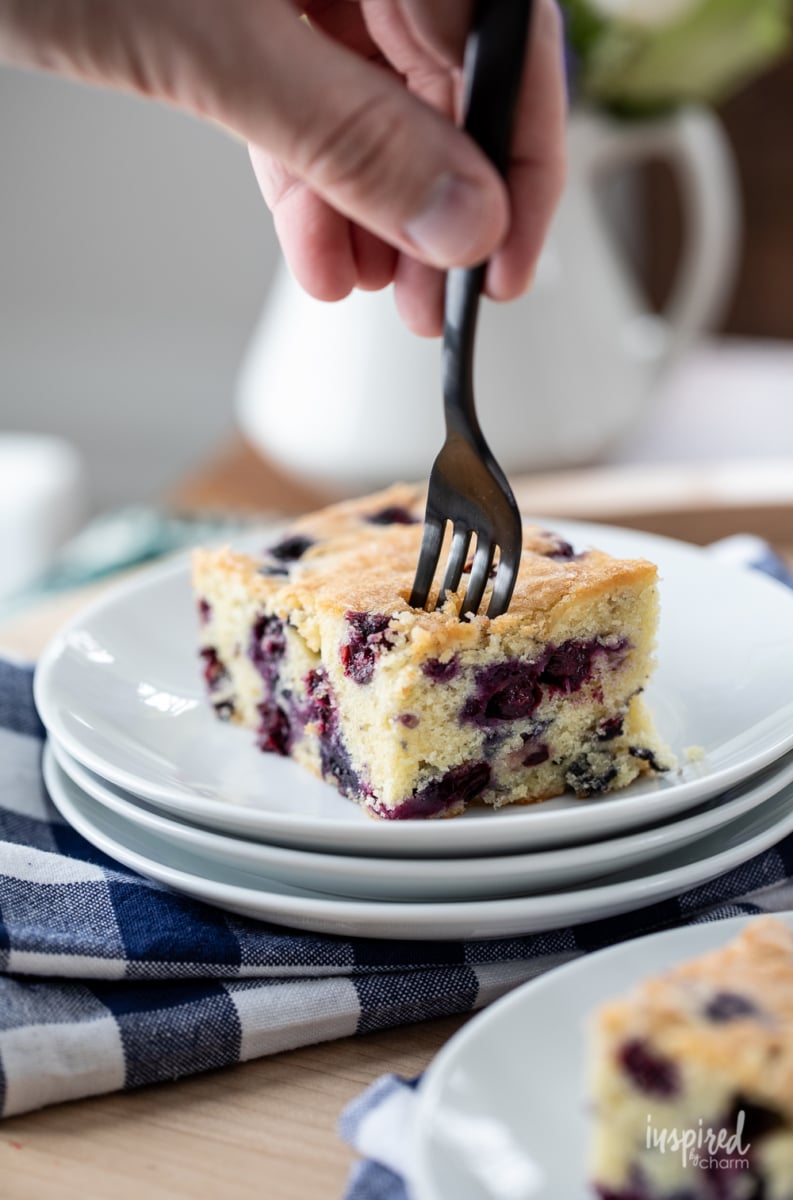 using a fork to get a bite size piece of blueberry cake