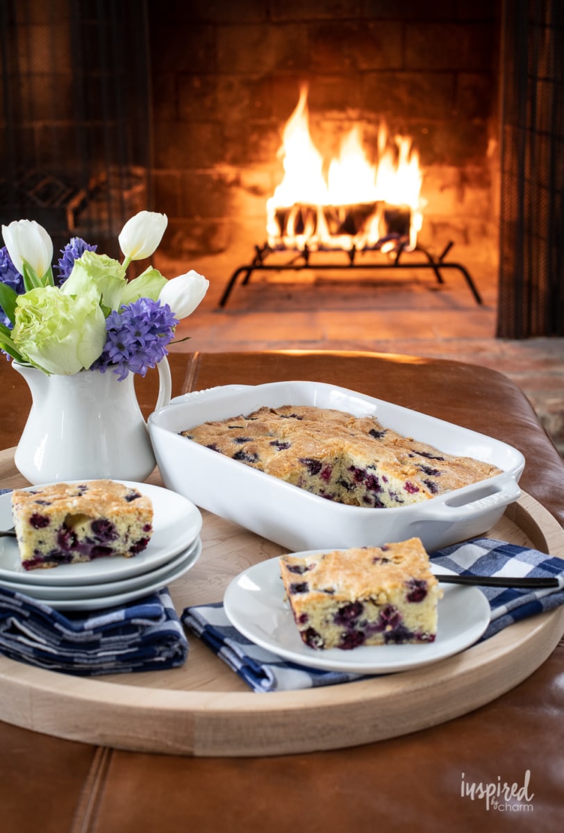 a baking dish of fresh blueberry cake with a fire in the background