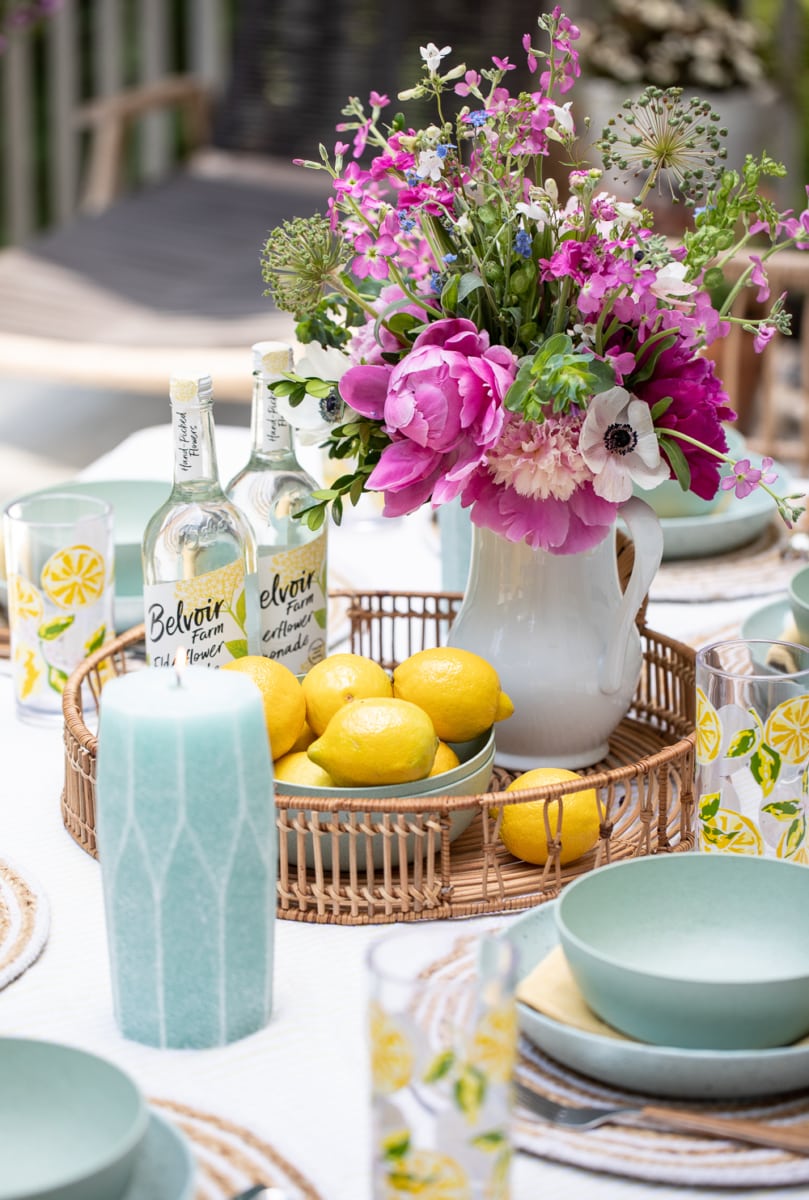 flowers and bowl of lemons on outdoor table setting.