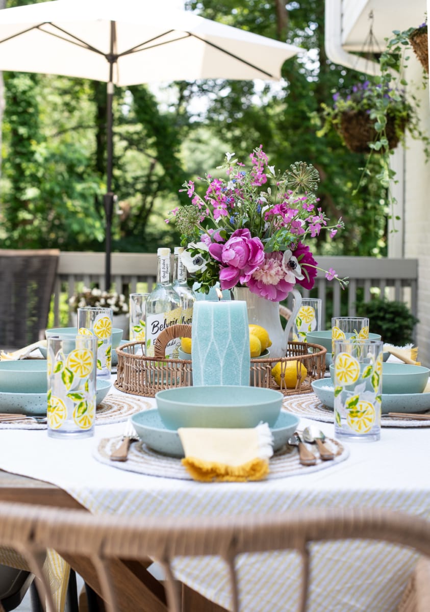 outdoor table setting with candles and flower arrangement in pitcher.