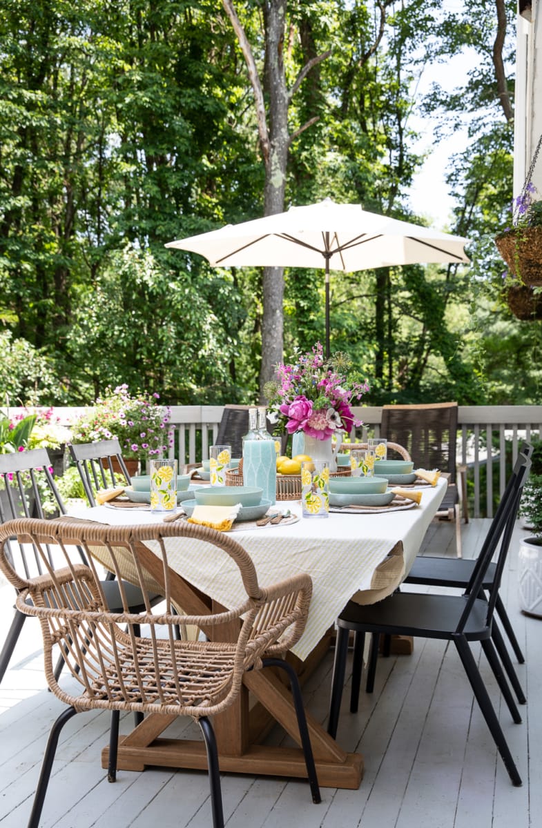 a dining table set-up outside on a deck.