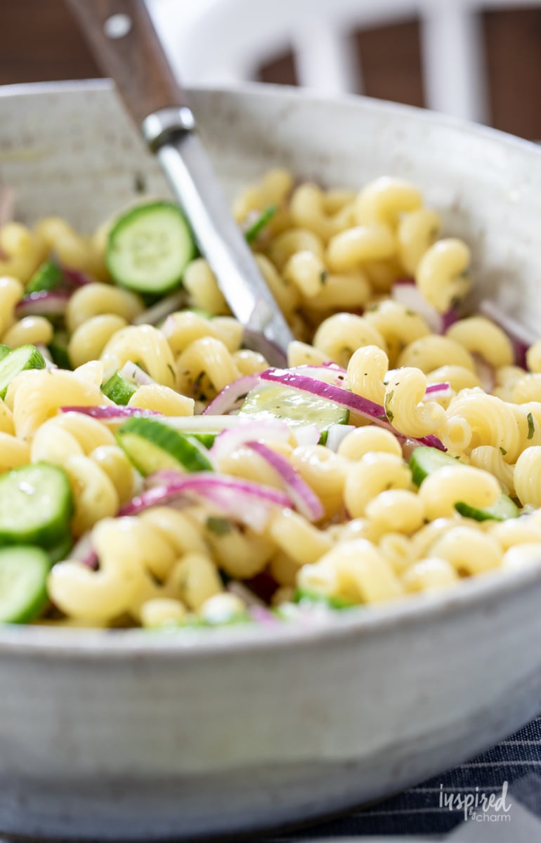 cucumber pasta salad in a big bowl with a serving spoon.