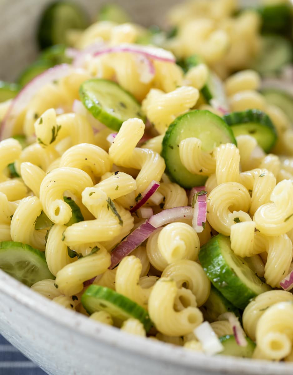 close up of cucumber pasta salad served in a large white bowl.