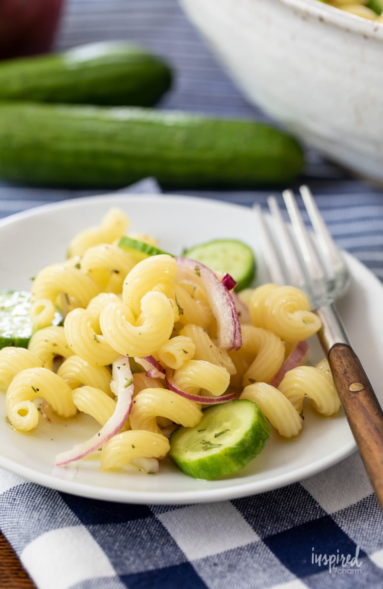 cucumber pasta salad on a small white plate with a fork.