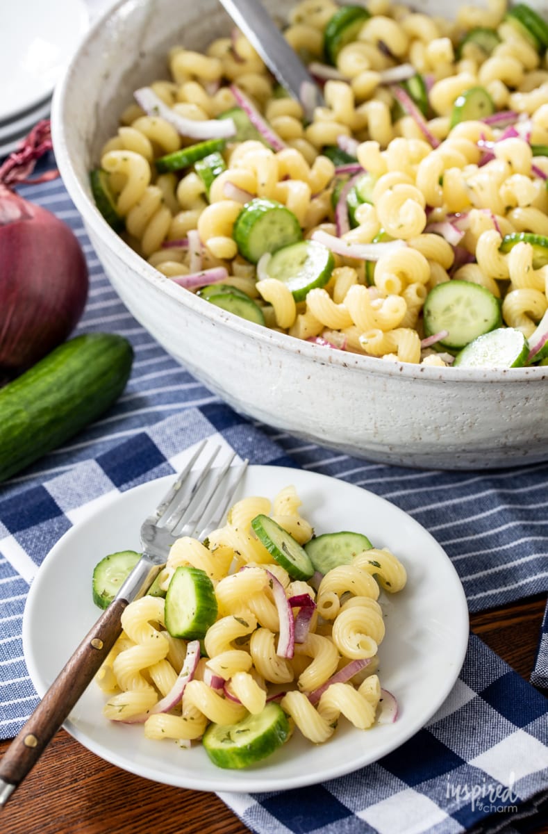 cucumber pasta salad in a large bowl and served on a plate with a fork.