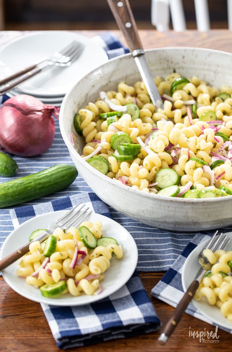 cucumber pasta salad served in a large bowl with two servings on small white plates.