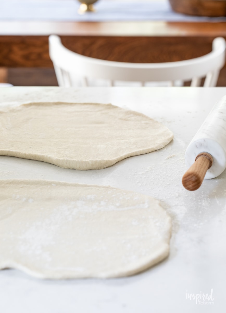 two circles of bread dough rolled out on a floured surface