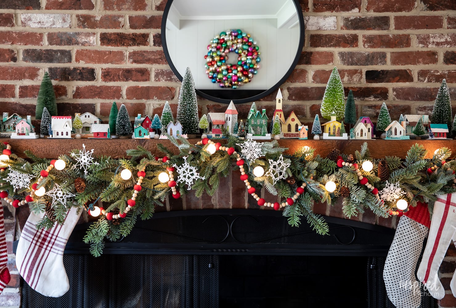 Putz House Christmas Mantel decorated with garland and vintage putz houses.