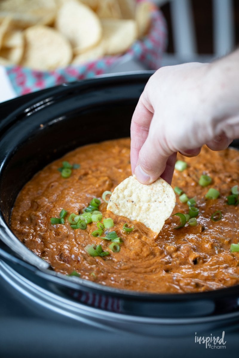 dipping a chip into Hot Chili Cheese Dip