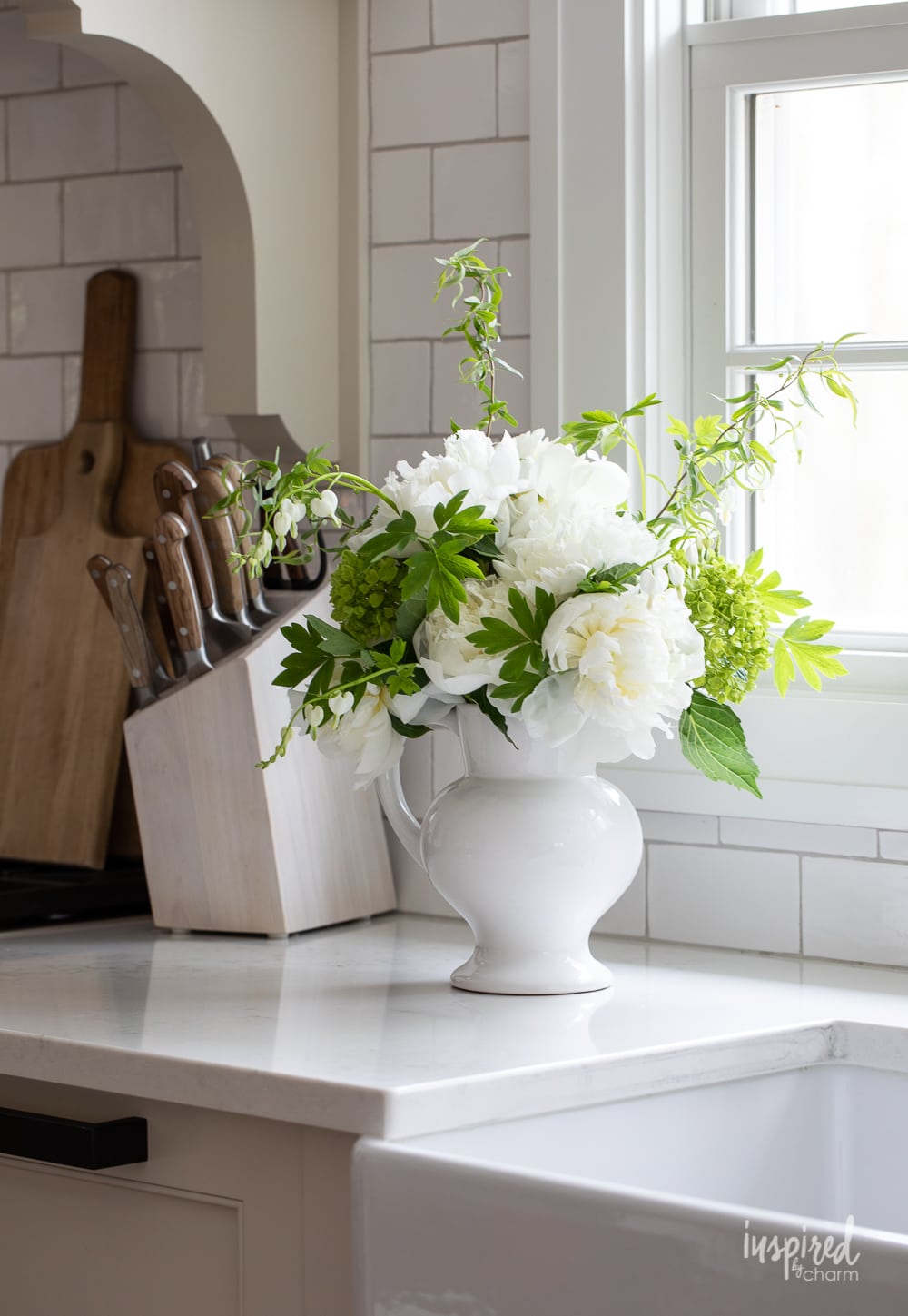 peony arrangement in a white vase on a countertop.