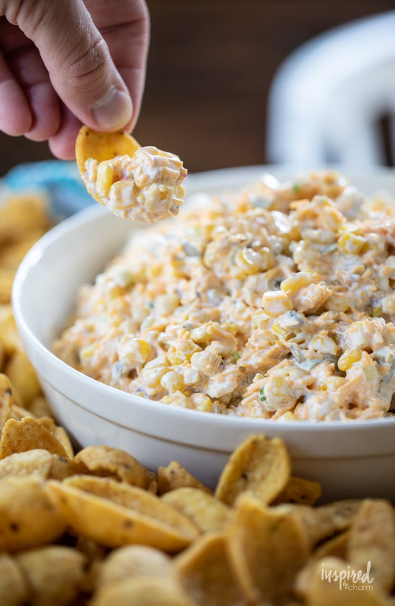 hand getting corn dip with Fritos.