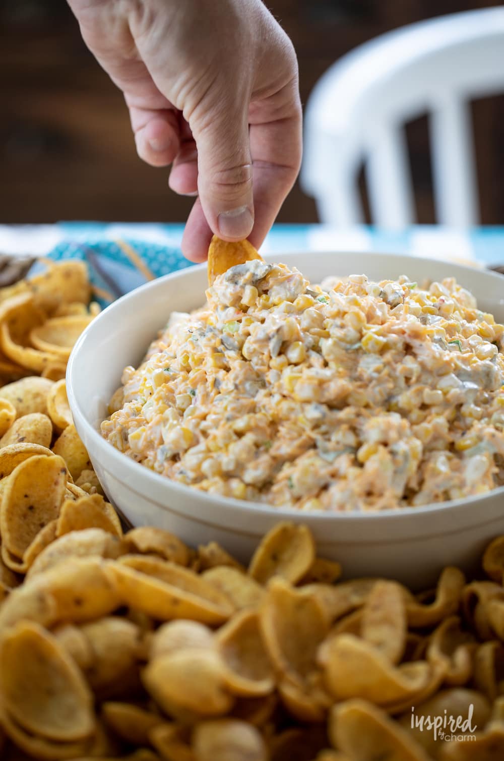 hand dipping into corn dip in a bowl.