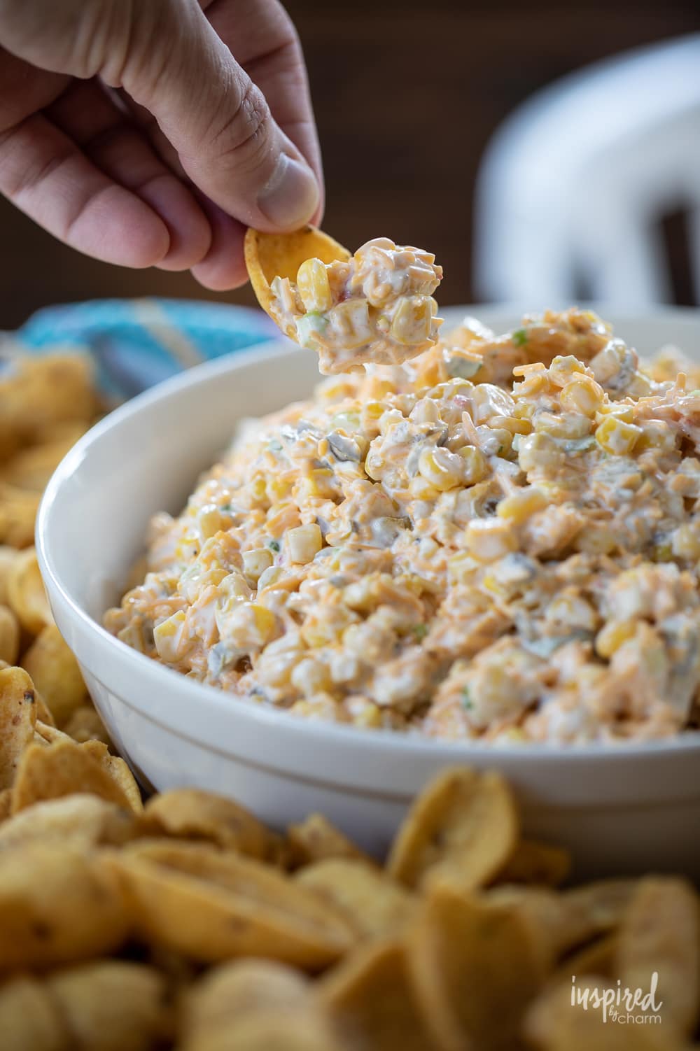 the best corn dip in a bowl with hand.