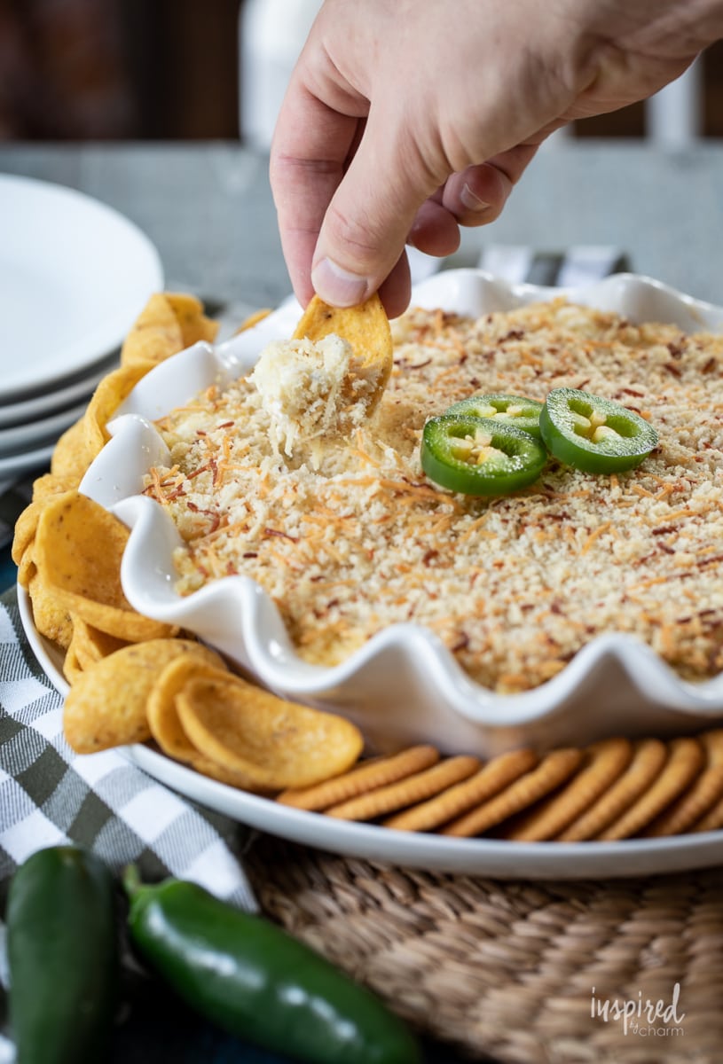 Jalapeño Popper Dip in dish with hand scooping dip.