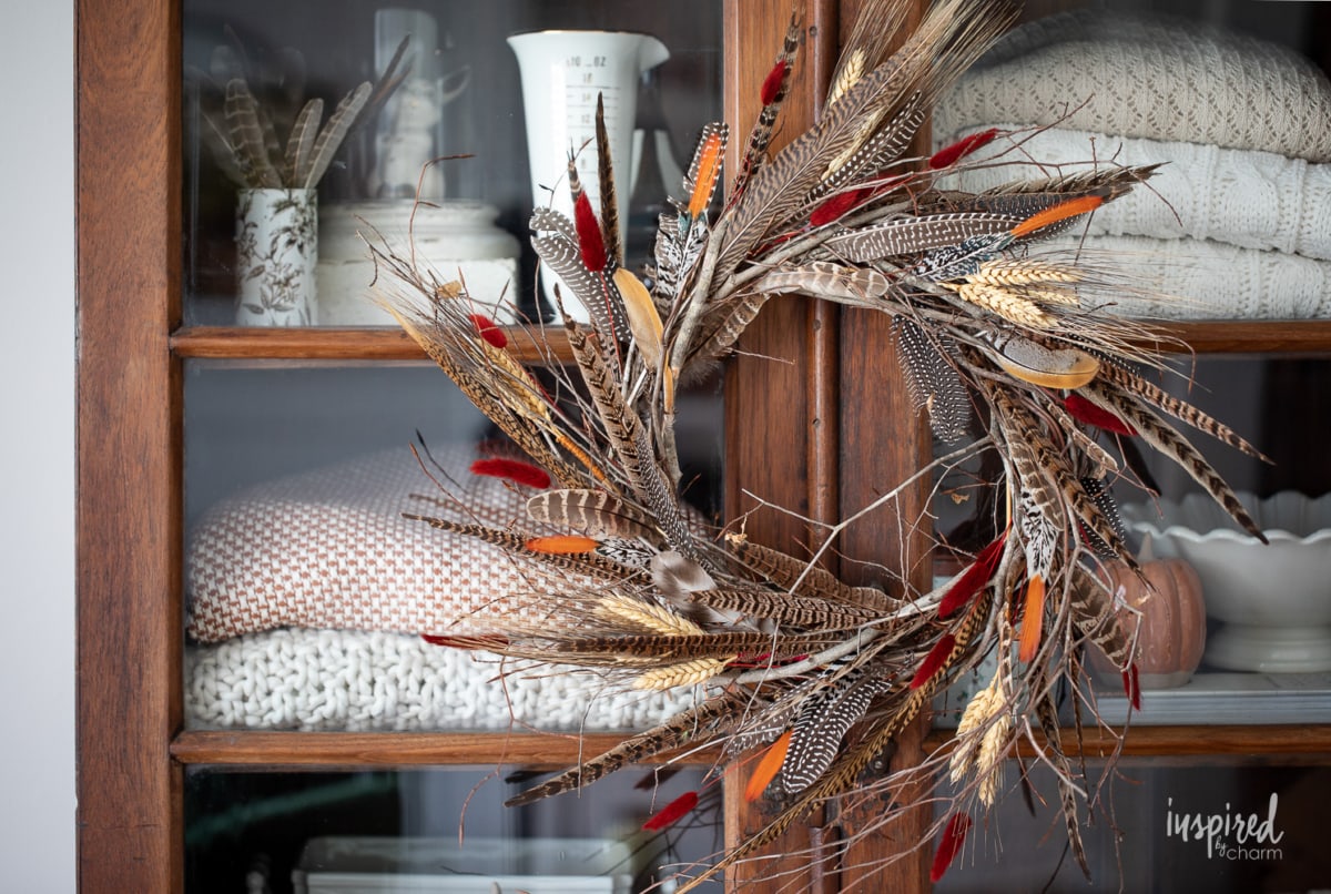 DIY Feather Wreath for Fall hung on cabinet.