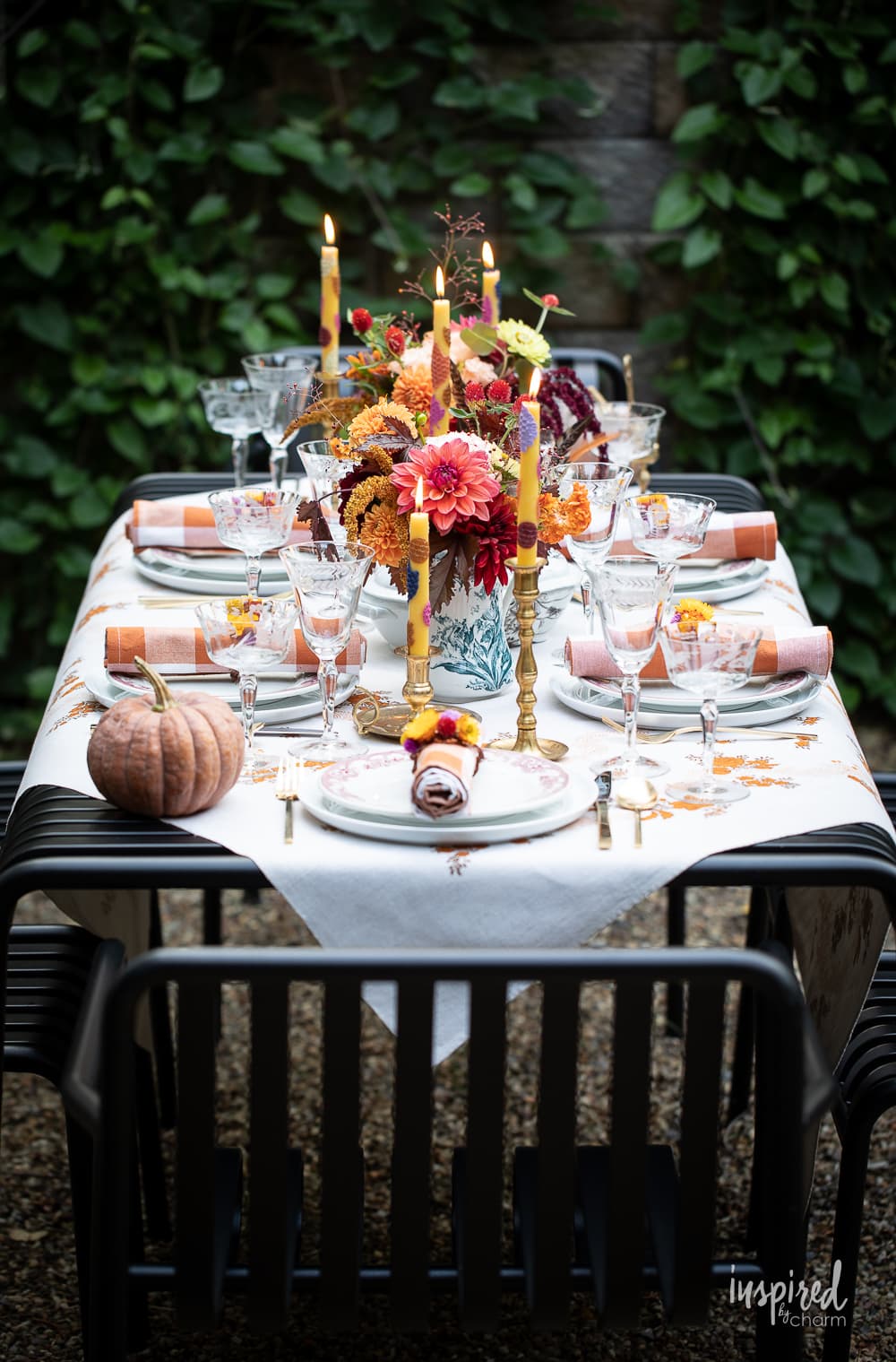 Vintage-Inspired Fall Tablescape set with candles, tablecloth, pumpkins and fall flowers.