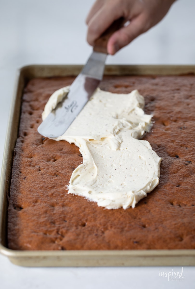 spreading Brown Butter Cream Cheese Frosting on pumpkin bars.