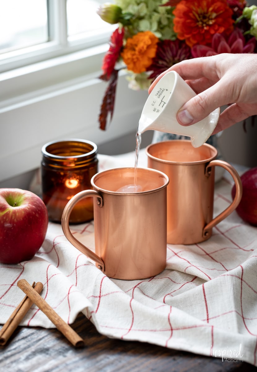 making Caramel Apple Cider Moscow Mule in copper mug.