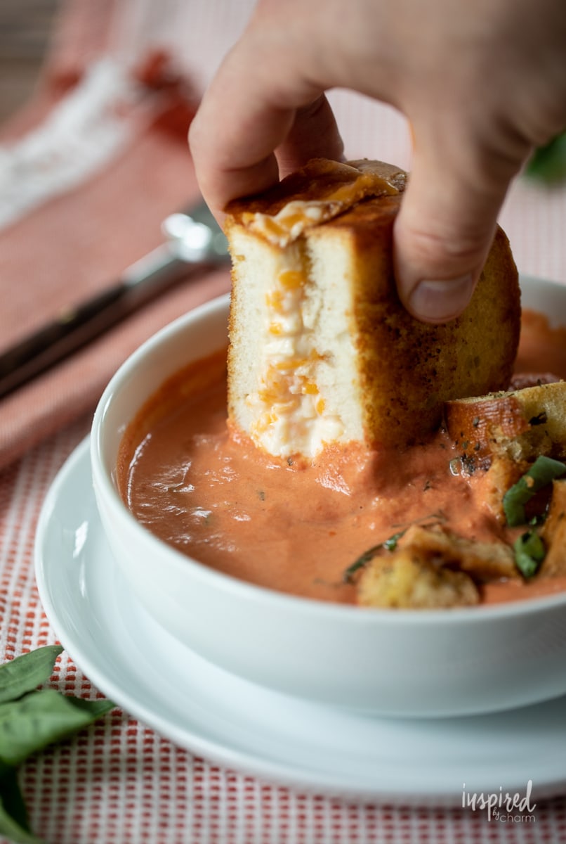 dipping Ultimate Grilled Cheese into tomato basil soup.