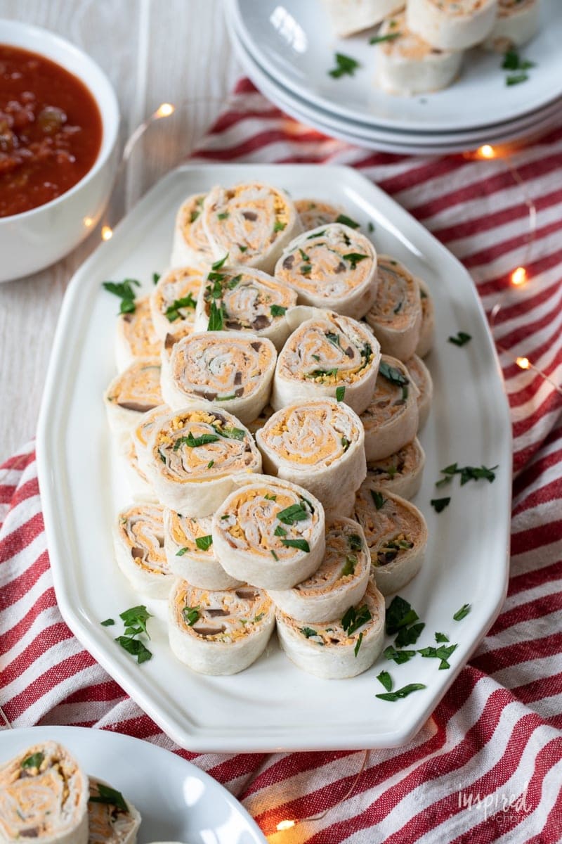taco pinwheels on a plate with a bowl of salsa.