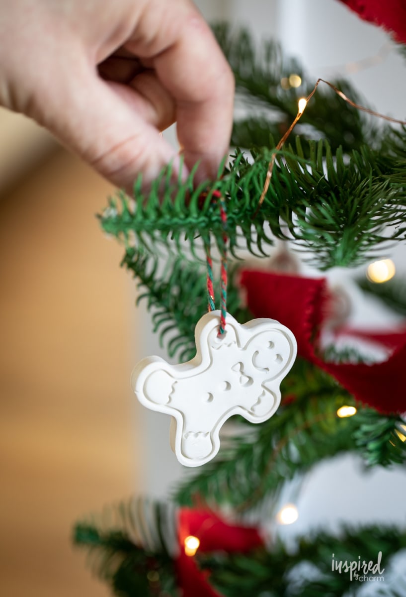 hanging a clay ornament on a tree.