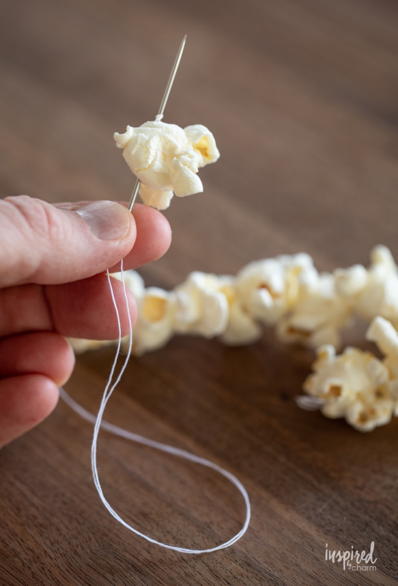 threading popcorn onto a needle and thread.