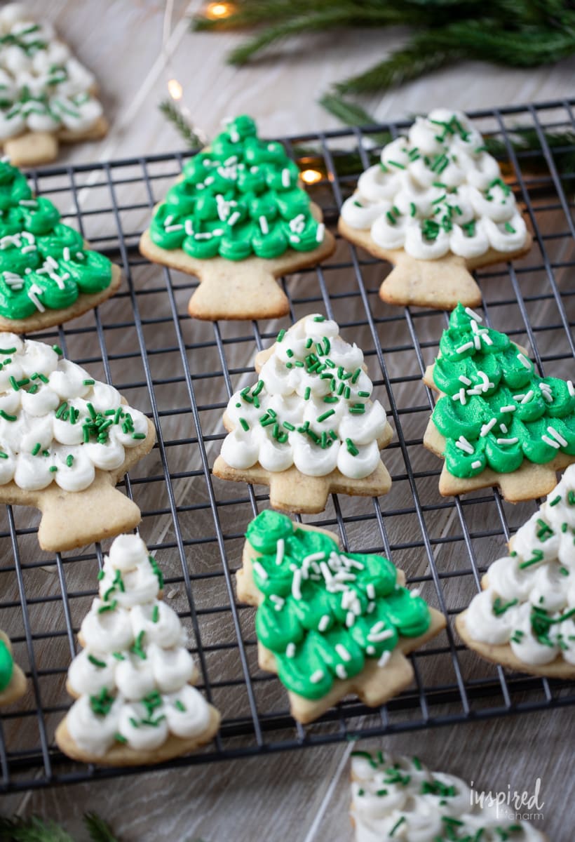 pine tree shaped frosted almond sugar cookies on a cooling rack.