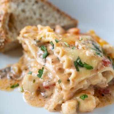 seafood lasagna on a plate with bread.