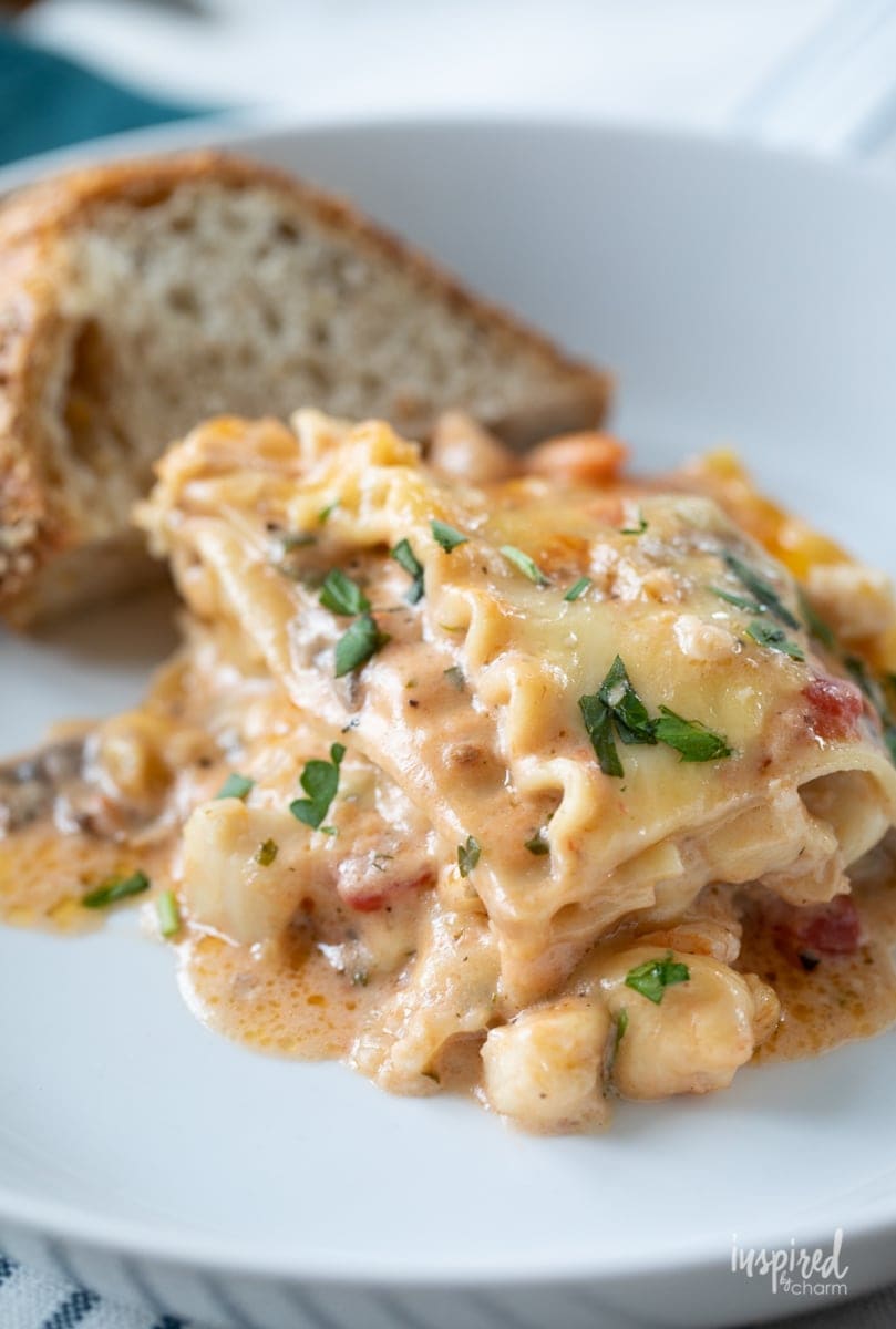 seafood lasagna on a plate with bread. 