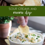 hand dipping into sour cream and onion dip in a bowl with potato chips and pretzels.