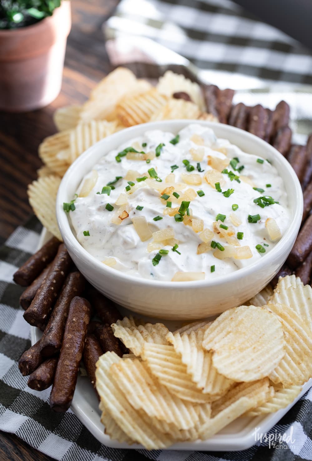 sour cream and onion dip in a bowl with potato chips and pretzels.