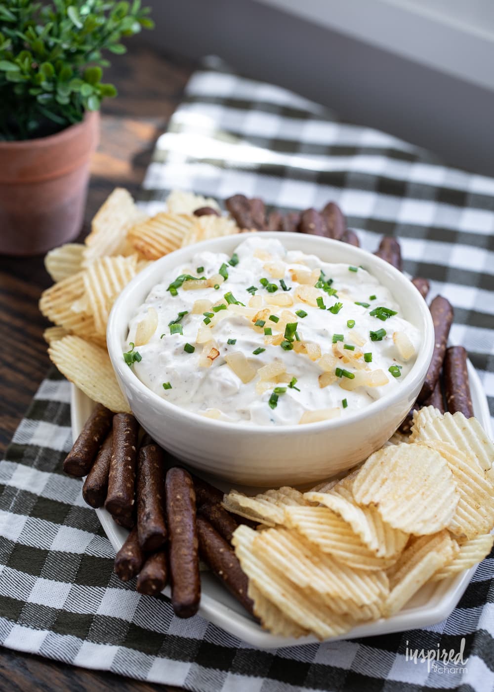 sour cream and onion dip in a bowl with potato chips and pretzels.