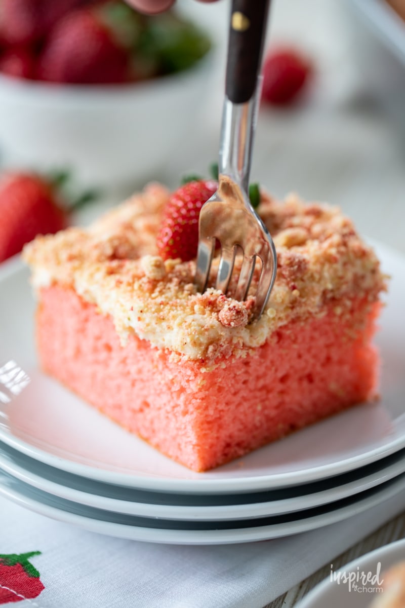 slice of strawberry crunch cake on a plate with a fork.