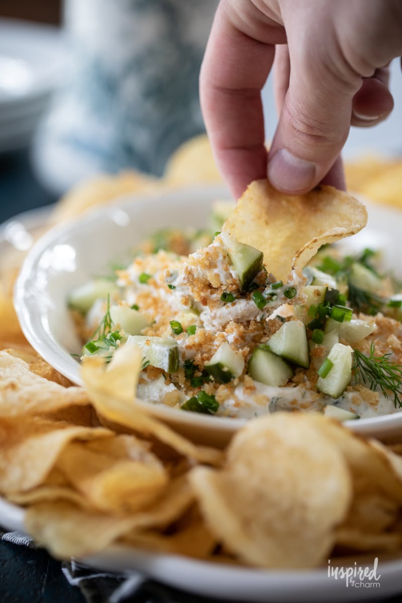 hand dipping potato chip into fried pickle ranch dip.