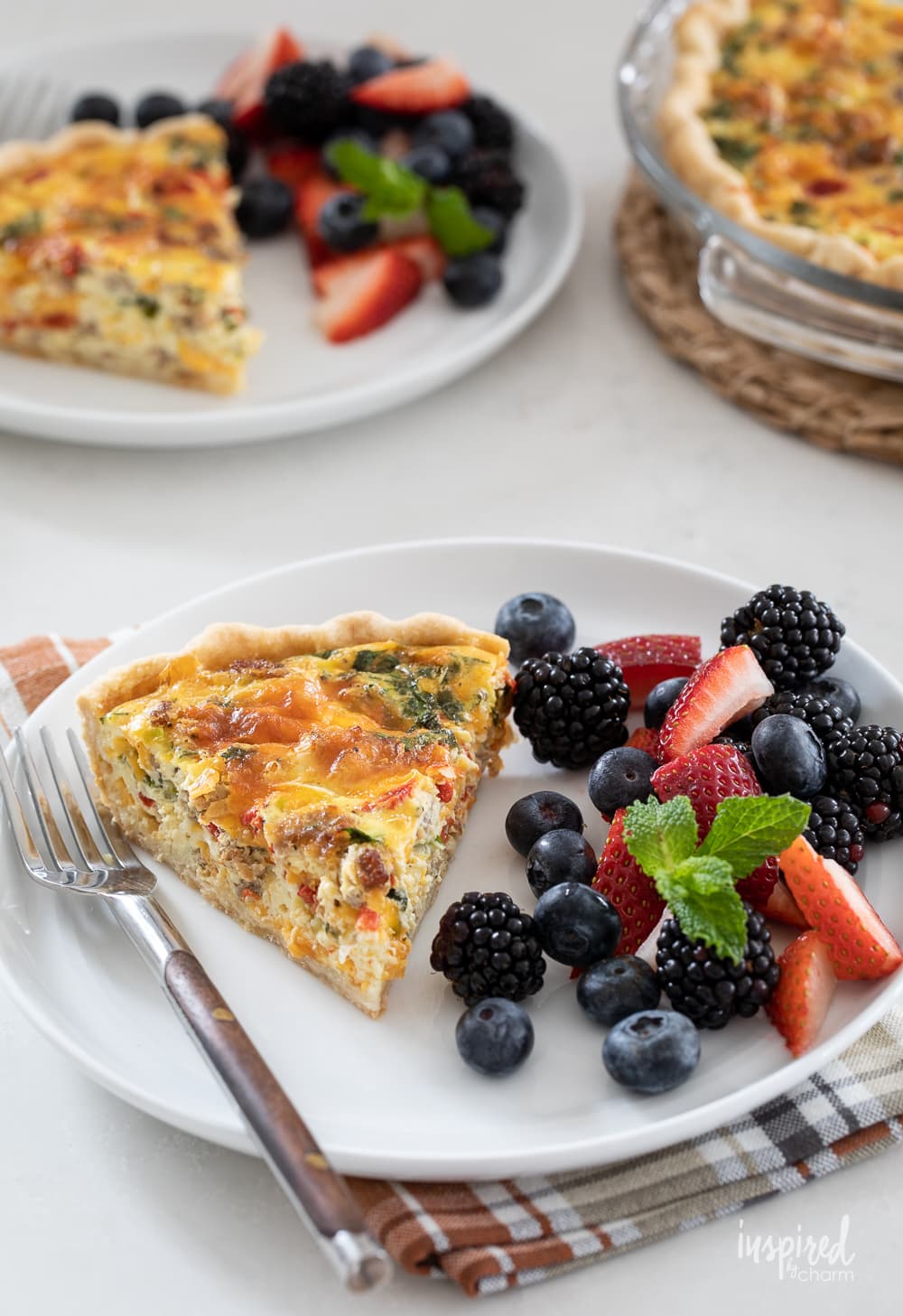 red pepper and sausage quiche on two plates with fresh berries. 