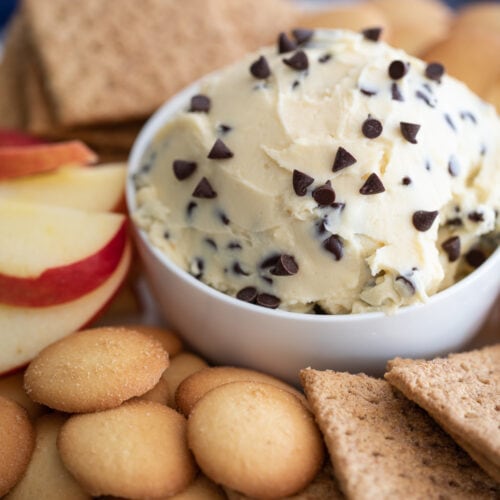 chocolate chip cheesecake dip in a bowl with cookies and apple slices.