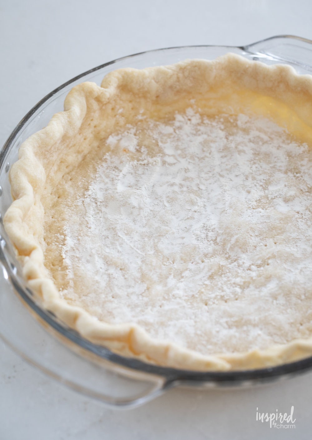 par baked quiche crust in clear pie pan.