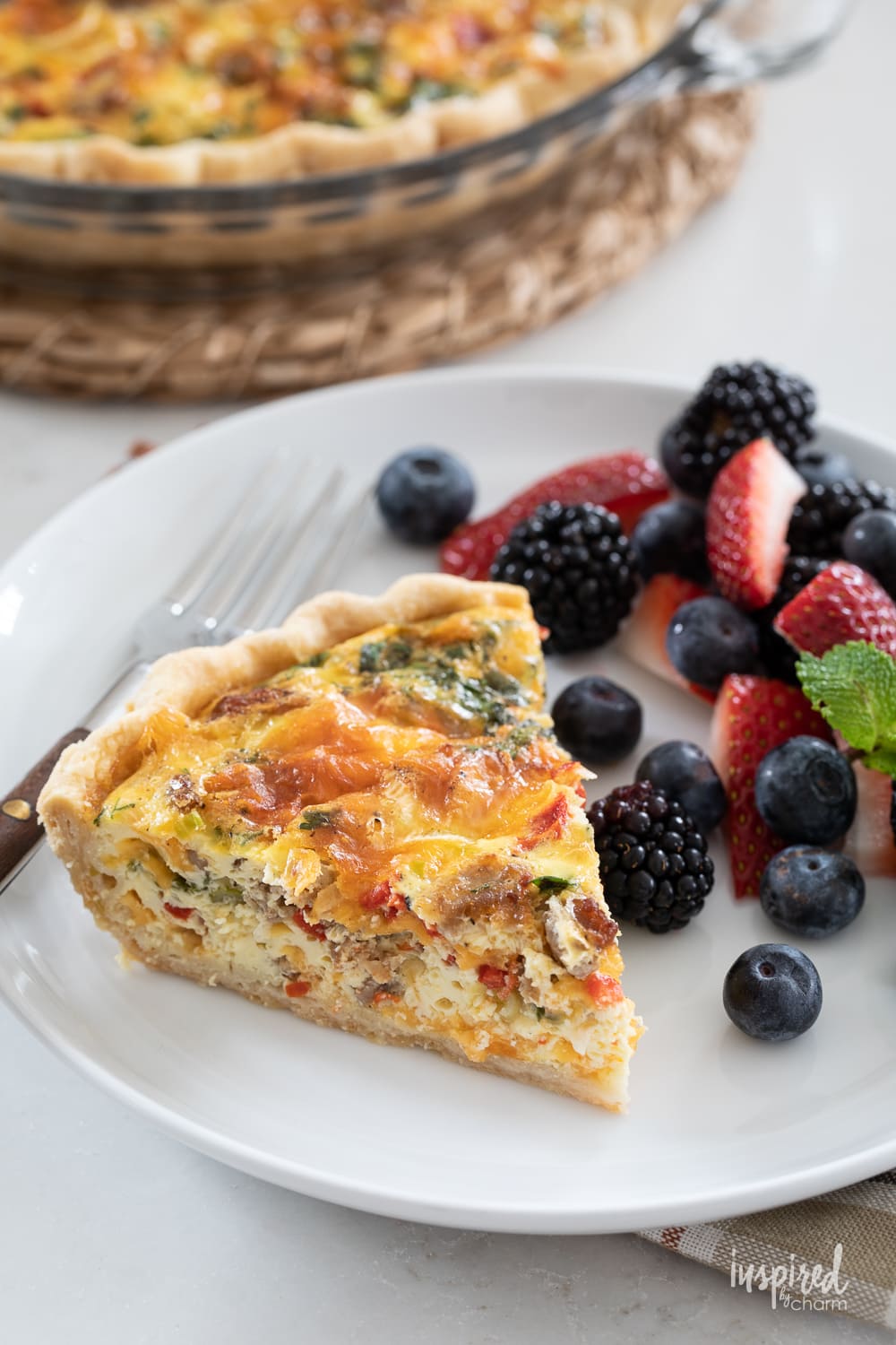 red pepper and sausage quiche on a plate with fresh berries.