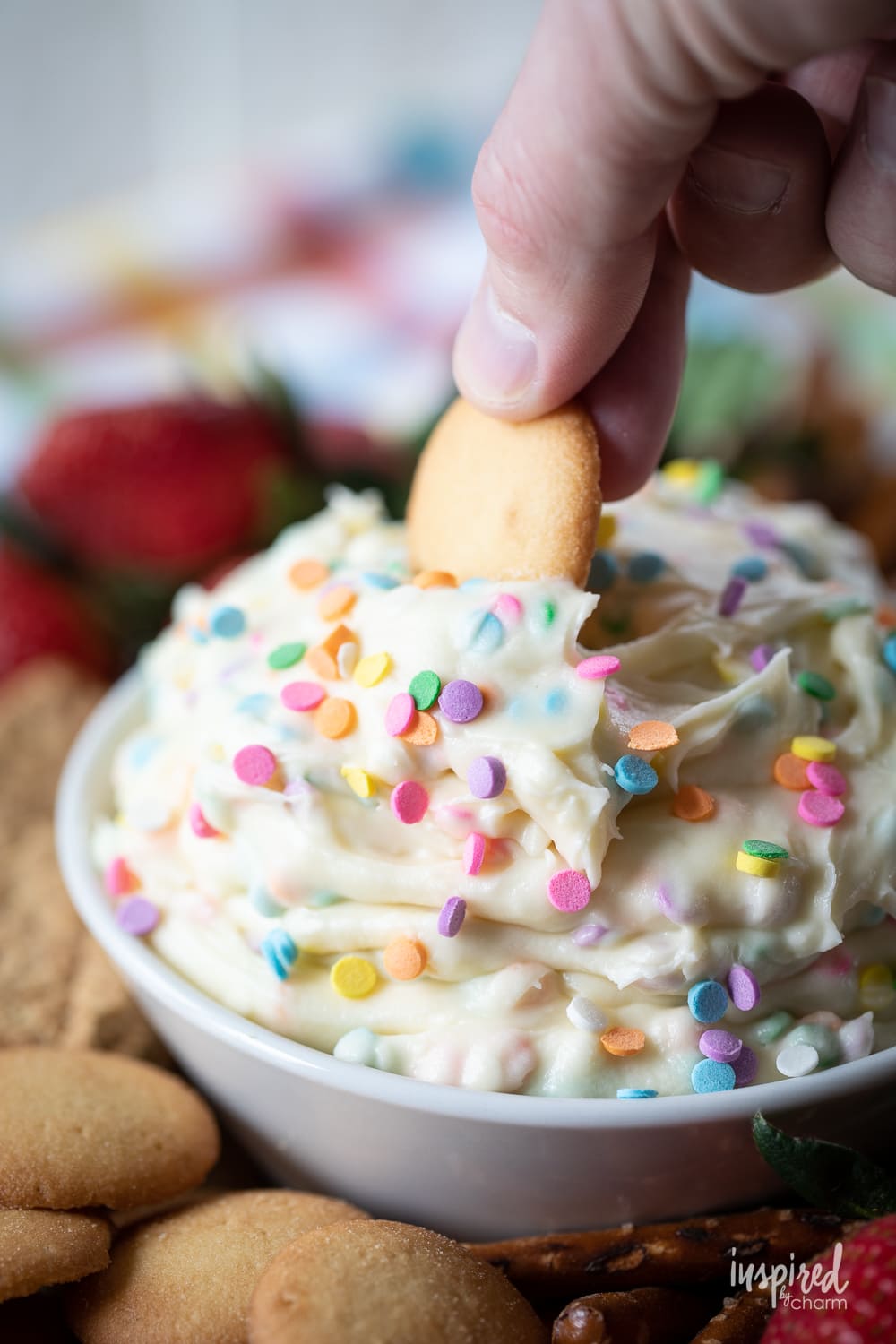 dipping a vanilla wafer cookie into funfetti dip.