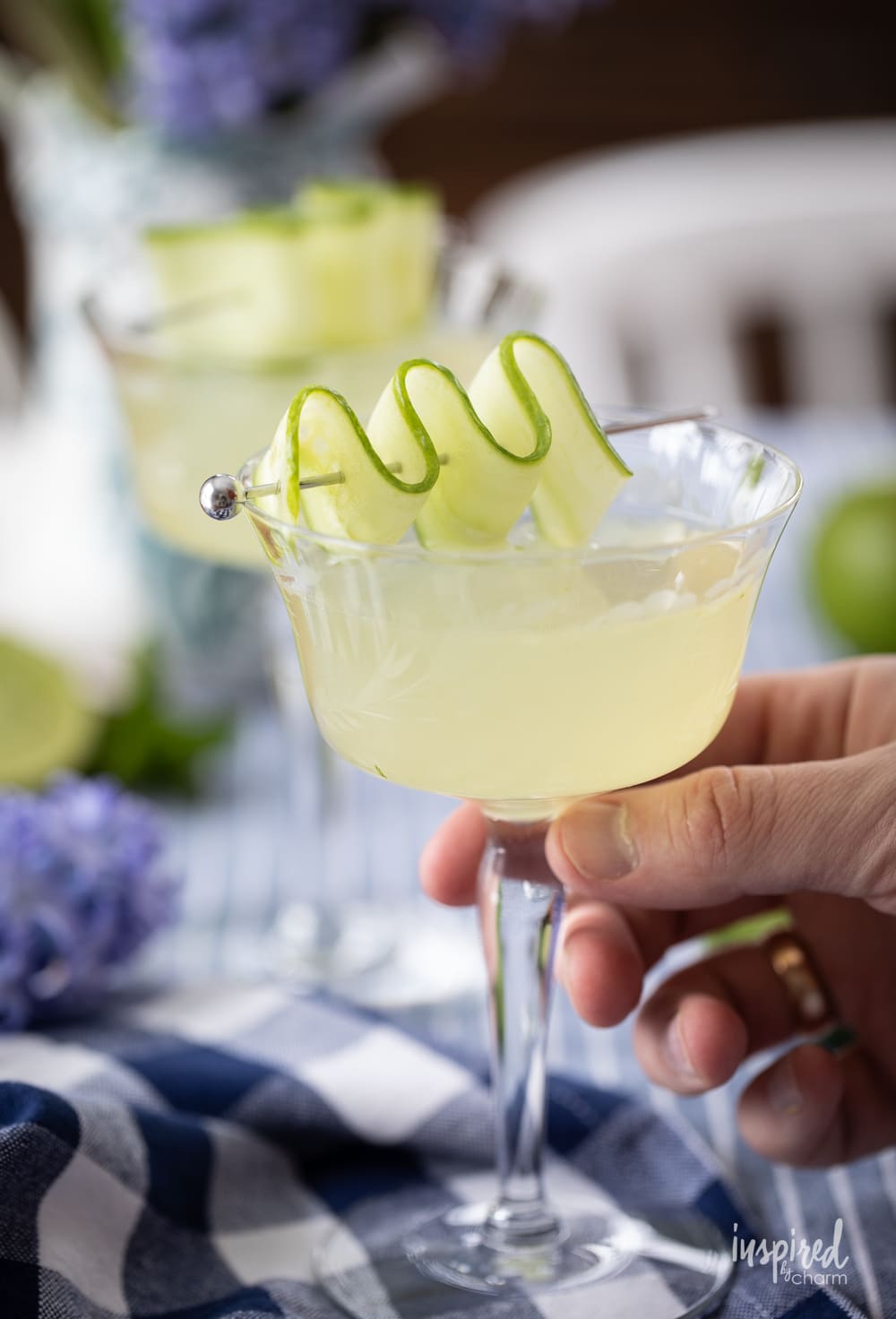 hand holding cucumber martini in coupe glass. 