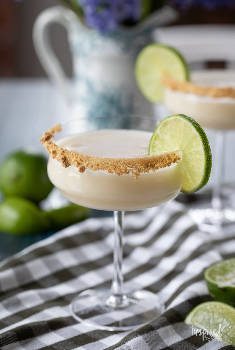 two key lime pie martinis in  glasses with a lime garnish.